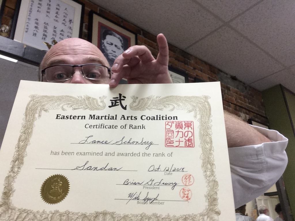 Lance holds up his grading certificate from his sandan grading, less than a year and a half before COVID.